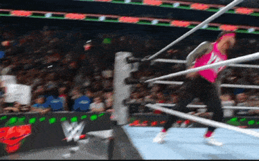 a wrestler in a pink shirt is in the ring