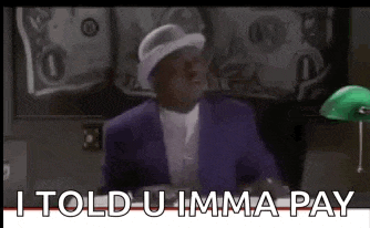 a man in a purple suit and white hat is sitting in front of a green lamp and talking .