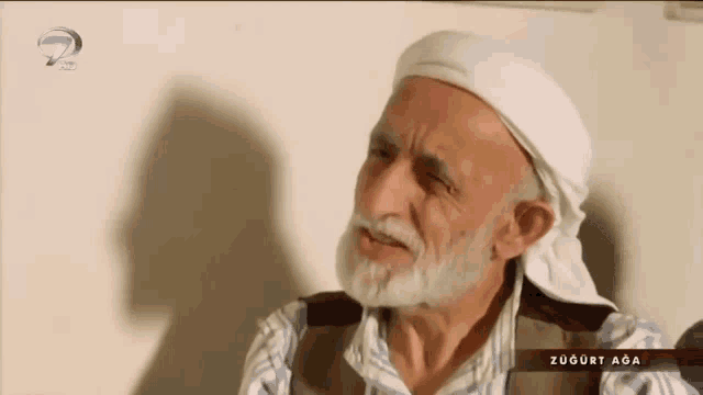 a man with a beard and a head scarf is on a tv screen with the words zugurt aga