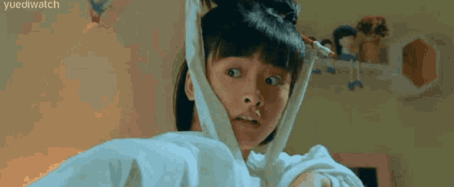 a young girl is holding a white shirt over her head .