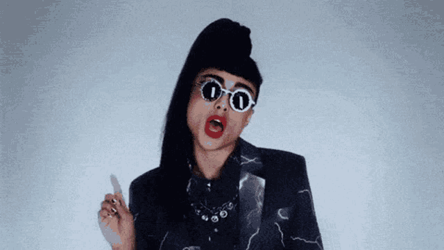 a woman wearing sunglasses and a ponytail is making a face .