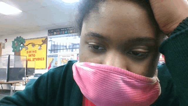 a girl wearing a pink mask in front of a bulletin board that says " swing into equal studies "