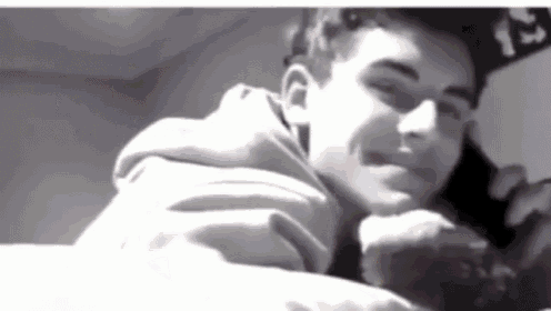 a black and white photo of a young boy laying on a bed