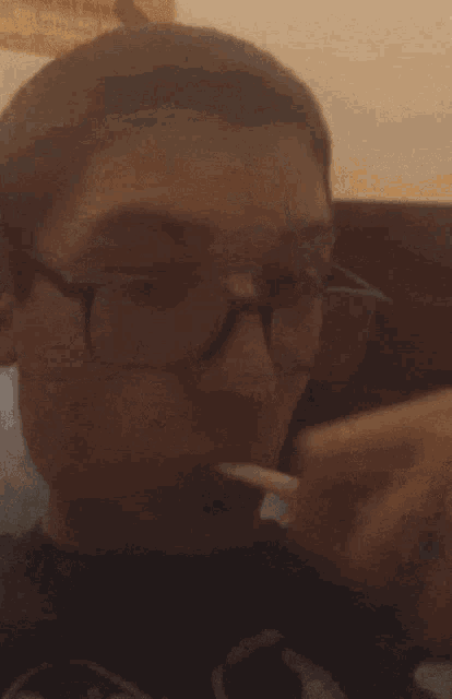 a man wearing glasses holds his hand to his nose