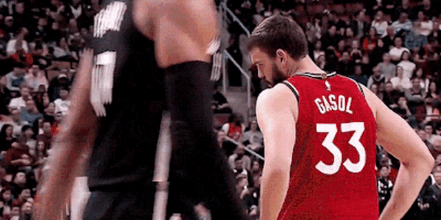 a basketball player wearing a red jersey with the number 33 on the back is standing next to another player .