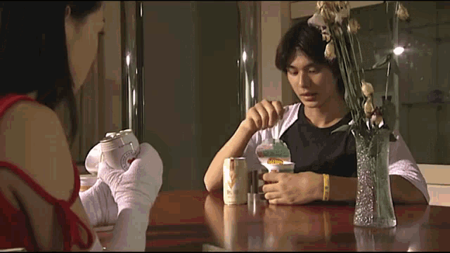 a man and a woman sit at a table with a can of vodka