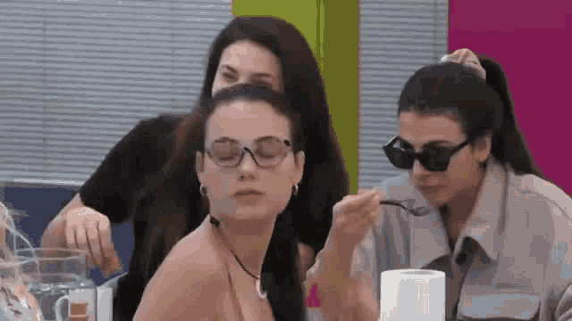 three women are sitting at a table with a roll of toilet paper .