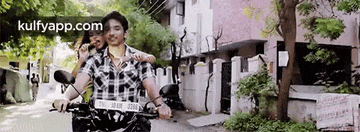 a man and a woman are riding a motorcycle down a city street .