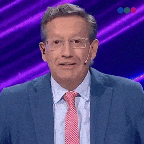 a man in a blue suit and red tie is standing in front of a purple background
