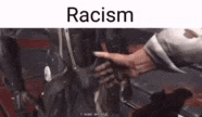 a person is pointing at a robot in a video game and the word racism is on the bottom .