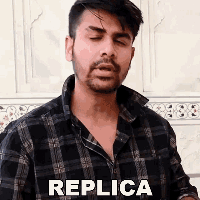 a man in a plaid shirt says replica in front of a white wall