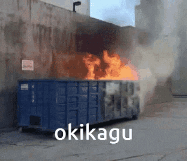 a dumpster is on fire and the word okikapu is on the bottom