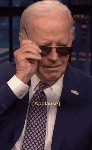 a man in a suit and tie is wearing sunglasses and the word applause is on the bottom