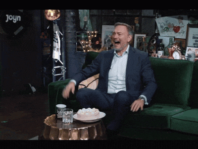 a man in a suit is sitting on a green couch with his mouth open