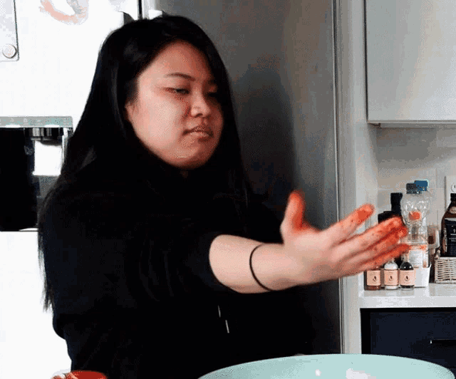 a woman with red paint on her hands is standing in front of a green bowl