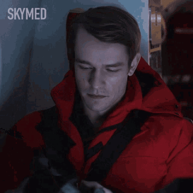 a man in a red jacket is wearing headphones and the word skymed is behind him