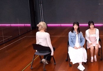 three women are sitting in chairs in front of a mirror in a room .