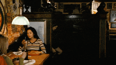 a woman sitting at a table with a plate of food and a bottle of wine