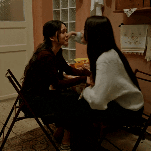 two women are sitting next to each other and talking