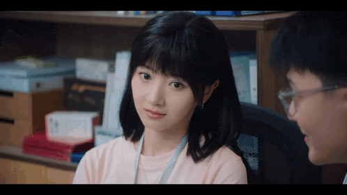 a woman in a pink shirt sits next to a man with glasses