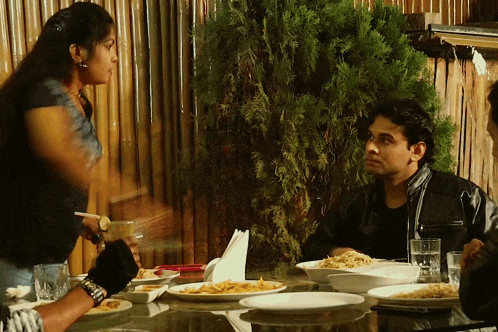 a group of people are sitting at a table with plates of food on it