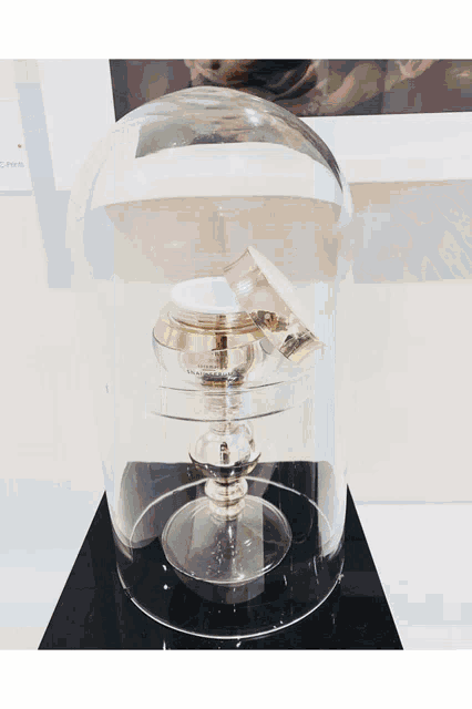 a glass dome with two jars inside of it with one that says ' chanel ' on it