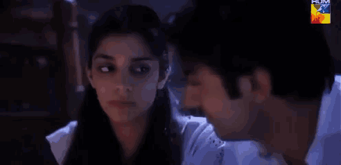 a man and a woman are looking at each other with their eyes closed in a dark room .