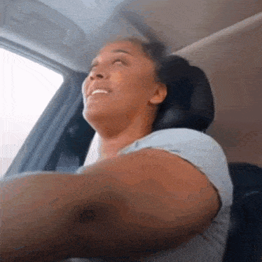 a woman is sitting in the driver 's seat of a car looking out the window .