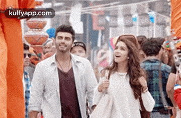 a man and a woman are walking down a crowded street and smiling .