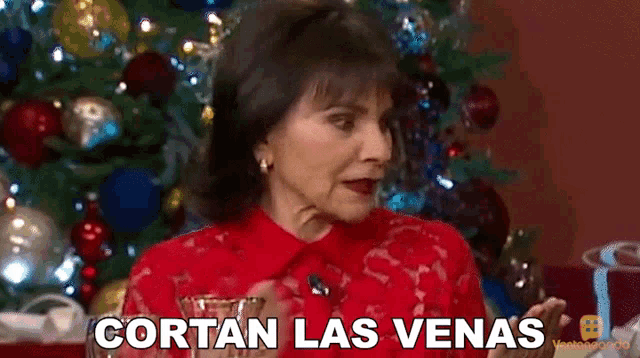 a woman in front of a christmas tree with cortan las venas written on the screen