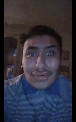 a man wearing a blue and white striped shirt is making a funny face with his mouth open