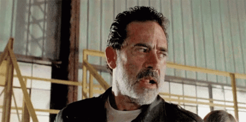 a man with a beard and a leather jacket is standing in a building .