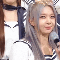a woman in a sailor suit is holding a microphone and smiling