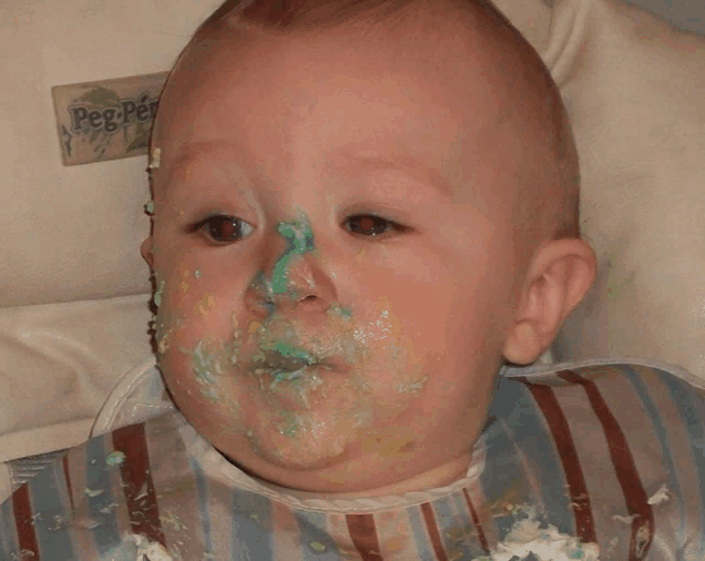 a baby with green frosting on his face is wearing a bib that says peg perego