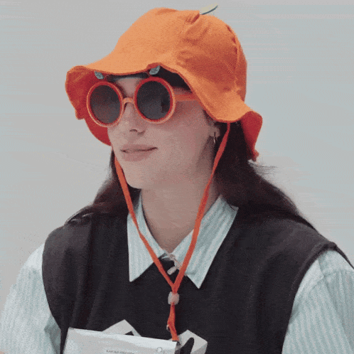 a woman wearing an orange hat and sunglasses is holding a kakao press