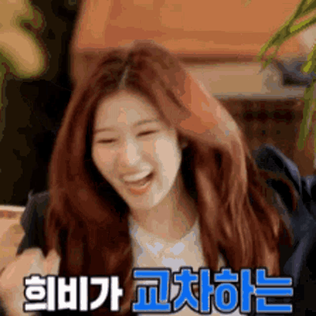 a woman with red hair is smiling and laughing with korean writing behind her .