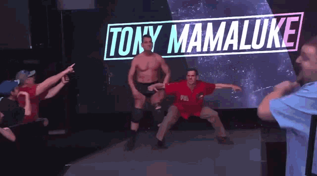 a man in a red shirt is dancing in front of a sign that says tony mamaluke