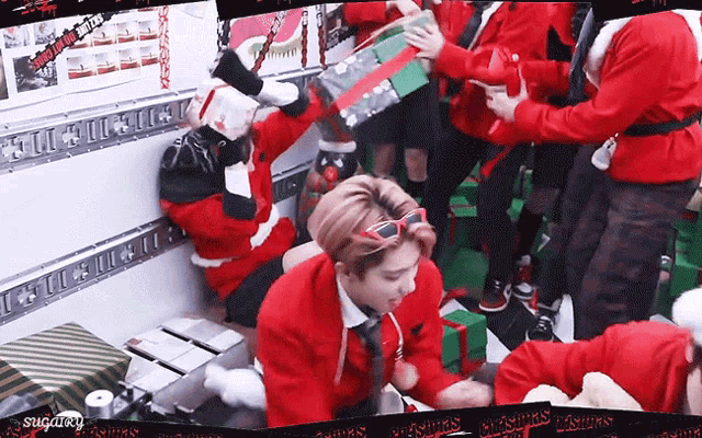 a group of people dressed in santa costumes are holding gifts .