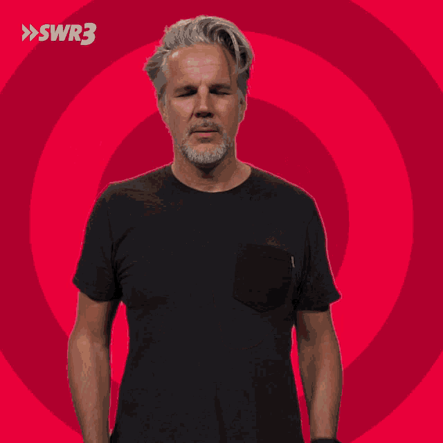 a man in a black t-shirt stands in front of a pink circle with the letters swr3 on it