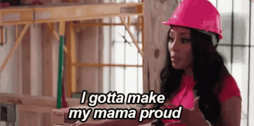 a woman wearing a pink hard hat is standing in a construction site .