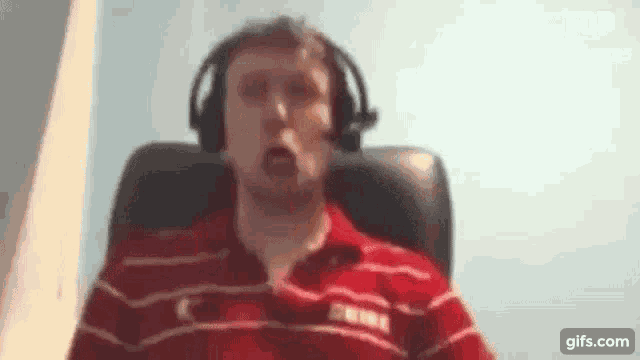 a man wearing headphones is sitting in a chair and making a funny face .