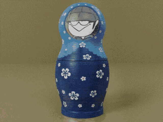 a blue green and orange nesting doll with a cartoon face on it