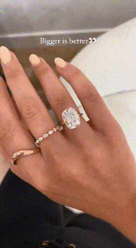 a close up of a woman 's hand with a ring on it and the words bigger is better .