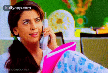 a woman is talking on a cell phone while holding a book .