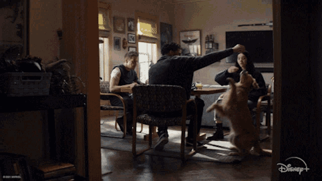 a group of people are sitting at a table with a dog and a disney logo in the corner