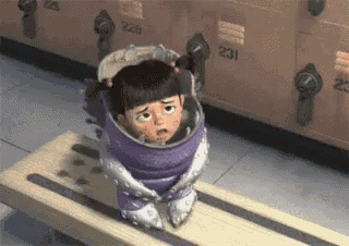 boo from monsters inc is wrapped in a purple blanket and sitting on a wooden bench .