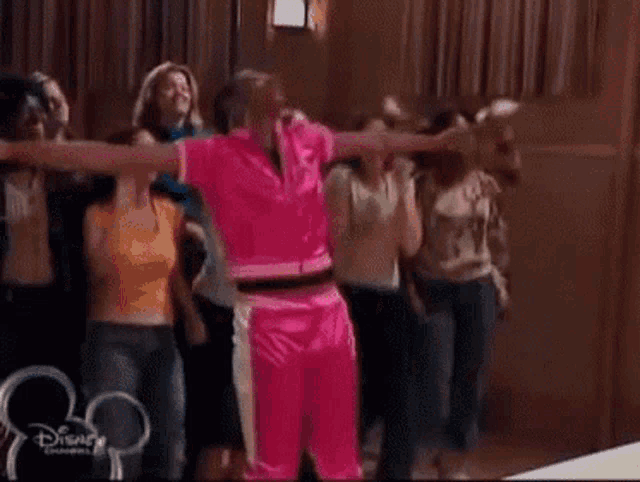 a group of people are dancing in a room with a disney logo on the bottom right corner .