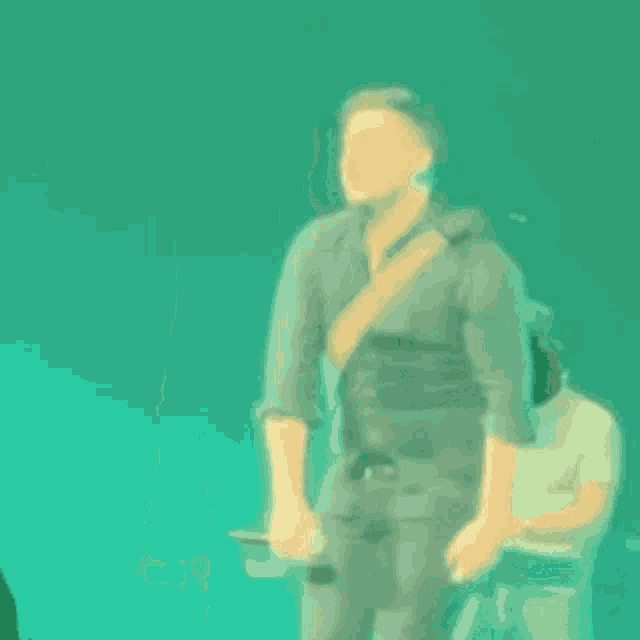 a man in a black shirt is dancing on a stage with a green background