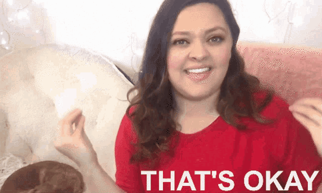 a woman in a red shirt is smiling with the words that 's okay below her