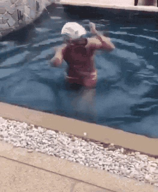 a woman is swimming in a pool with a white hat on